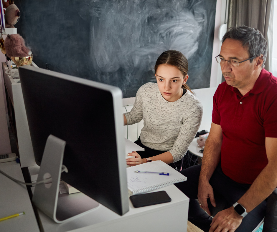 Homeschooling dad and daughter looking to a computer