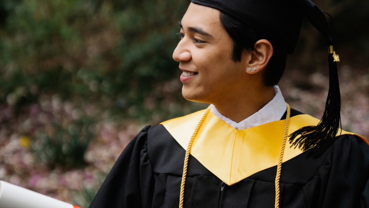 smiling man in academic dress holding diploma