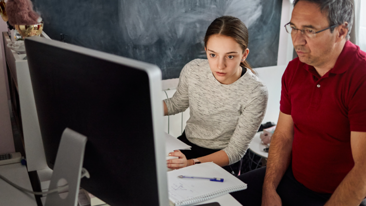 Homeschooling dad and daughter looking to a computer